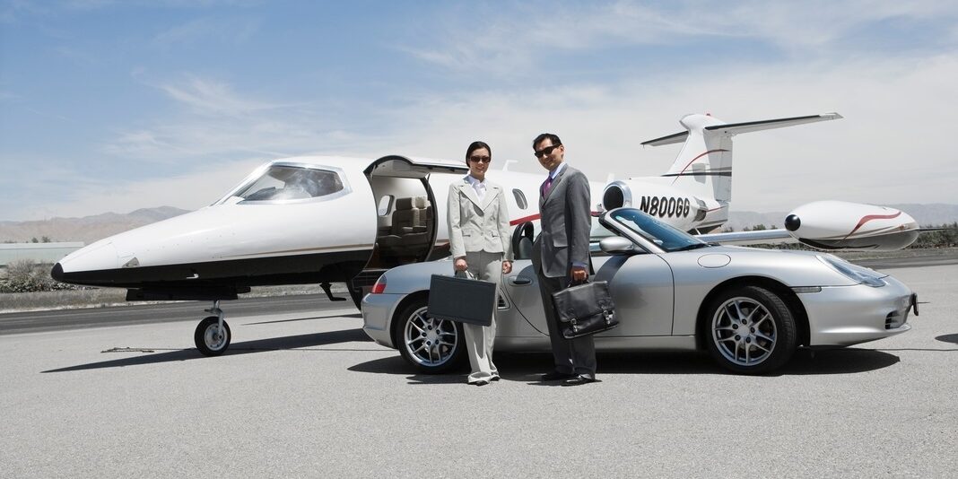 Two people in front of a car and private jet.