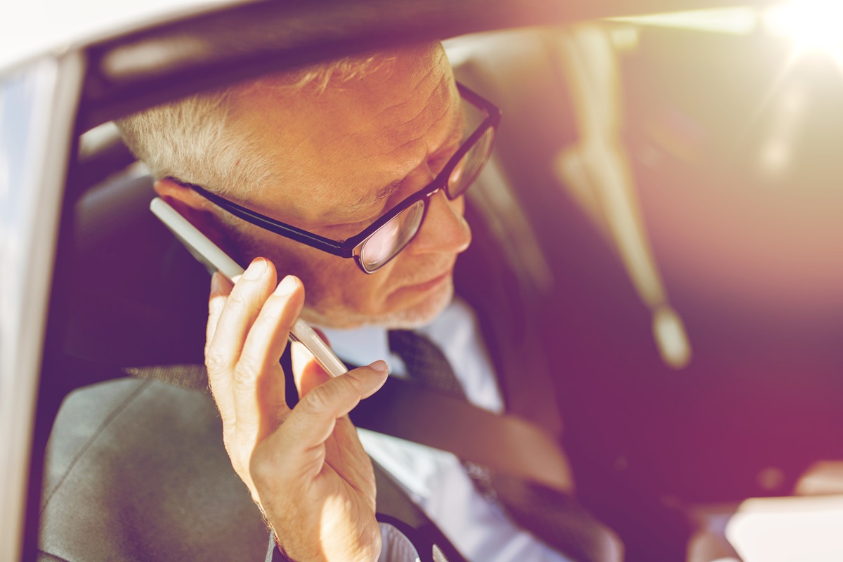 Senior businessman on a cell phone in the backseat of a car.